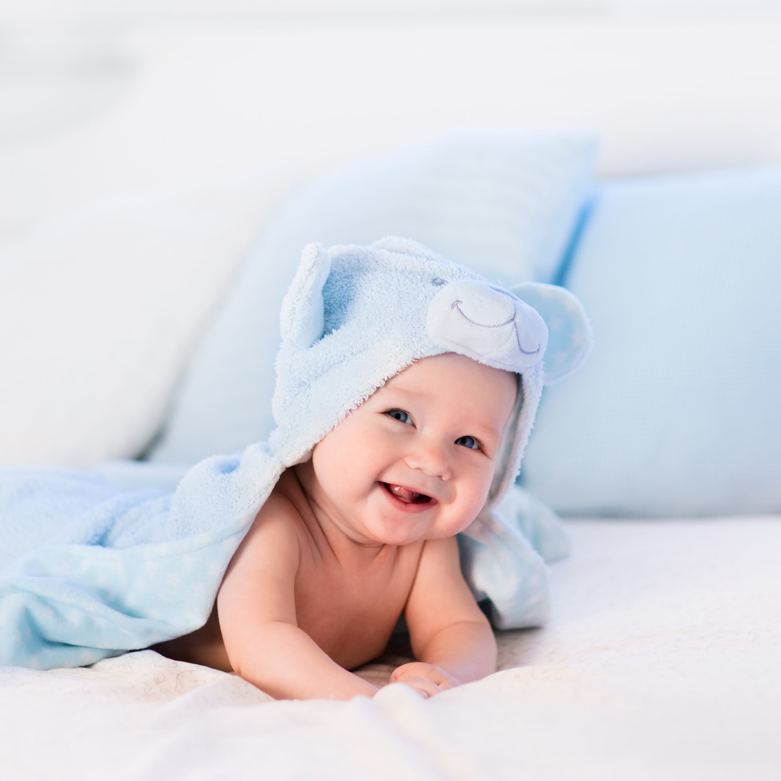 Baby Boy In Blue Towel On White Bed